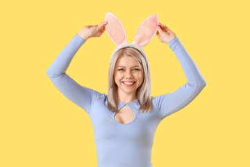 Beautiful woman in bunny ears on yellow background. Easter celebration