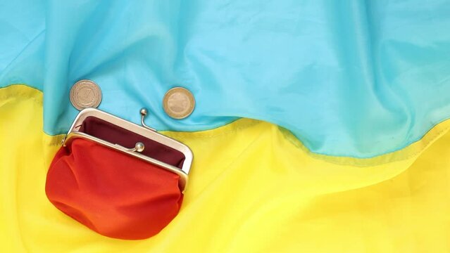 Polish zlotys and cents and kopecks are thrown into a red wallet that lies on the Ukrainian flag, business and finance, investments