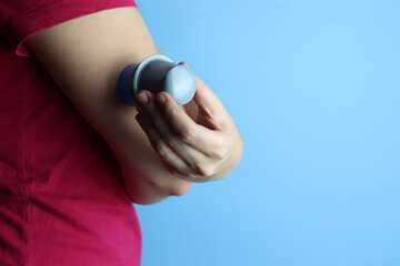 Woman applying a continuos glucose monitoring (CGM) in the arm with a copy spac in the right