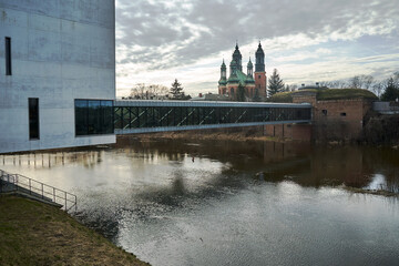 modern building, pedestrian bridge and historic defensive walls over the Warta River in Poznan - obrazy, fototapety, plakaty