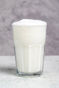 Sparkling buttermilk. Close-up. A glass of ayran on a gray background