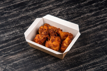 Fried BBQ chicken wings in lunch box  on black background