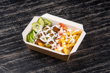 Falafel balls with fries and cucumber in lunch box