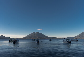 Boats in Water and Atitlan Lake in Guatemala. Long Exposure. Volcano in Background. Morning Light.