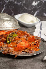 iskender kebab. Traditional Turkish cuisine flavor with tomato sauce and butter. iskender kebab on dark background