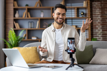 Indian man vlogging from home, discussing lifestyle in a cozy living room setting