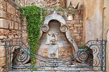 Old ottoman fountain of the late 18th century, with religious writings in ottoman alphabet and protected by metal railing, in the old town of Nafplio, in Peloponnese region, Greece, Europe. 
