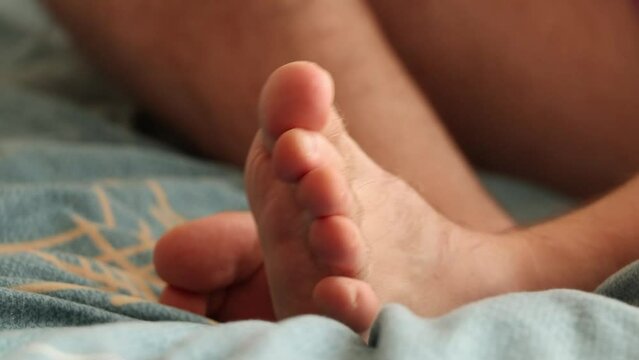 A man cuts his toenails with a broken toe on the bed at home, doing a pedicure himself