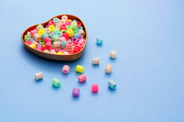 Heart shaped container containing colorful cylindrical plastic beads