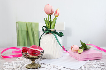 Spring mood: a bouquet of tulips in a white vase among gifts and sweets - Powered by Adobe