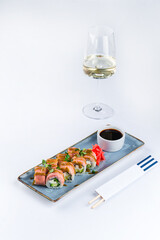 Rolls with tuna fish, cream cheese, avocado, greens and sauce with a glass of wine.