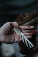 Naklejka premium Close-Up of Male Haircut: Hairdresser Trimming Hair in Modern Barber Style