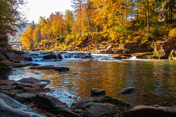 Obraz premium Stones on the bank of a mountain river against the background of autumn trees
