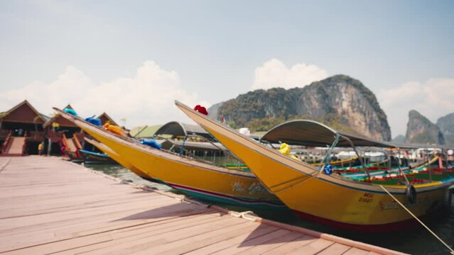 Boats are moored in the sea in the harbour. Colorful thai boats moored by the rocky shore in the blue sea during holiday time. Tourist attraction with pier, tourism, enjoy travel, adventure concept.