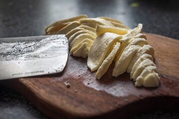 Chopped mozzarella ball into slices on wooden cutting board