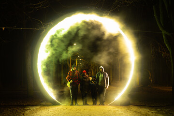 Illuminated portal with fog and smoke in the middle of the road. Silhouettes of people in the...