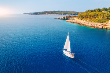 Aerial view of sailboat on blue sea at sunset in summer. Travel in Sardinia, Italy. Tropical...