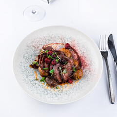 Veal cheeks with smashed potatoes and porto sauce with cranberries and microgreens with a glass of wine.