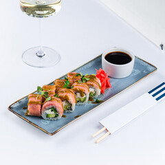 Fresh rolls with tuna fish, cream cheese, avocado, greens, ginger and sauce with a glass of wine.