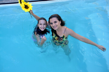 mãe e filha juntas felizes em piscina 