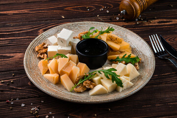 Snack cheese plate for wine: parmesan, feta, gouda, honey and walnuts.