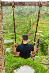 A young man enjoys a swing overlooking rice terraces on the popular island of Bali.