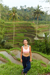 A young slender woman stands on rice terraces on the popular tourist island of Bali.