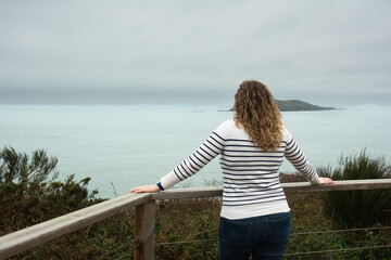 Une jeune femme en pull marin qui regarde la mer en Bretagne-France