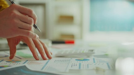 A young talented analyst solves complex analytical problem, looking for the necessary options for calculating indicators. Asian professional employee working with data charts. Counting with calculator