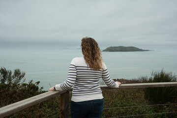 Une jeune femme en pull marin qui regarde la mer en Bretagne-France