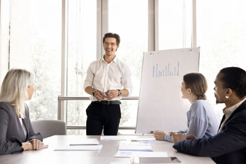 Young male boss make flip chart presentation for company client. Group of multiethnic...