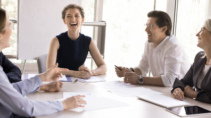 Joyful team members having conversation during seminar or morning briefing in modern conference room, laughing, joking enjoy friendly atmosphere with teammates. Business, communication, training event