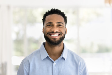 Cheerful handsome young African man head shot front portrait. Happy positive attractive male entrepreneur, startup leader, business professional in casual looking at camera with toothy smile