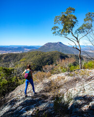 Obraz premium adventurous girl rock climbing to the top of mount may, dangerous climb in mount barney national park, queensland, australia;