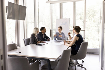 In modern conference room group of multiracial teammates solve joint task, share solutions,...