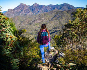 Fototapeta premium backpacker admires the panorama of australian mountains in mount barney national park; majestic view from the top of mount may, queensland, australia