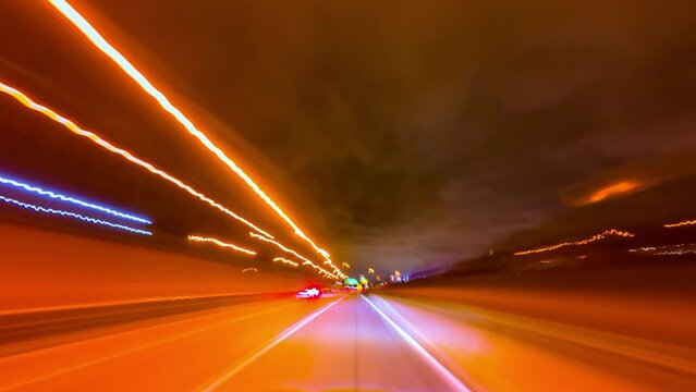 Fast car ride through city at night in rays of street lights, long exposure. Reflection of rays neon signs and lights, in windshield of auto. Theme a quick moved automobile on town and nightlife.