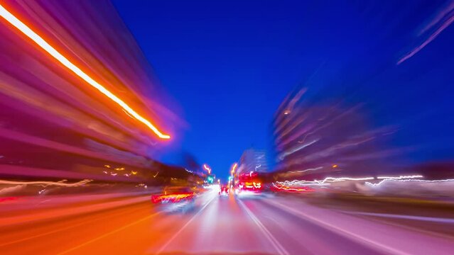 Travel on high way during night timelapse. Long exposure car POV at night traffic lights in the dark evening. Fast busy city life downtown, urban lights trails on highway, road transport time lapse.