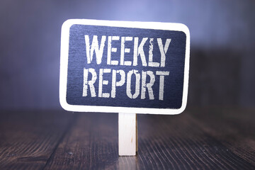 WEEKLY REPORT text on notebook with pen on pink background