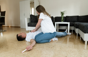 First aid. Smart young woman trying to resuscitate and doing CPR on an unconscious man lying on the...