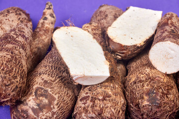closeup of taro root vegetable, eddo malanga, purple background