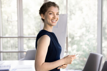 Young happy businesswoman, creative profession representative, boss pose in office with digital tablet. Comfort usage of modern tech for business, startup launch, project fulfillment, new program user