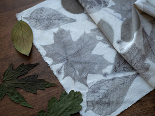 Eco-printed fabric and dried leaves on the wooden table. Natural dye experiment
