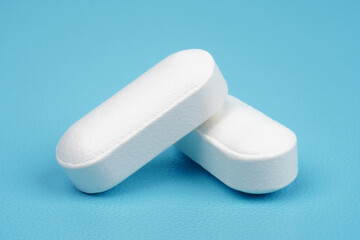 Long shaped white medical tablet isolated on blue background