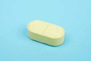 Single yellow tablet against blue background