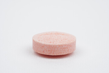 Single closeup pink medical tablet on white background