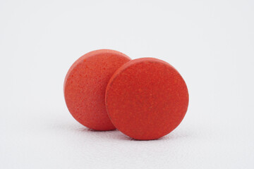 Closeup of two red tablets isolated on white background