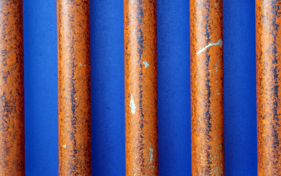 Vertical orange-brown metal bars against a blue background texture abstract