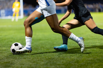 Close up action photo of two soccer players competing in a soccer game. Offensive player trying to score and dribble the ball towards goal.