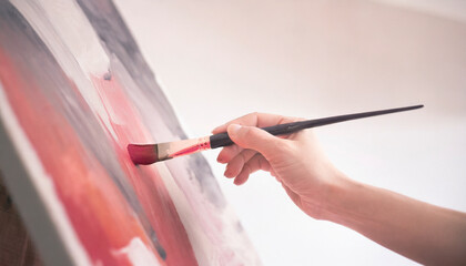 Woman's hand painting an expressionist painting in red and black color